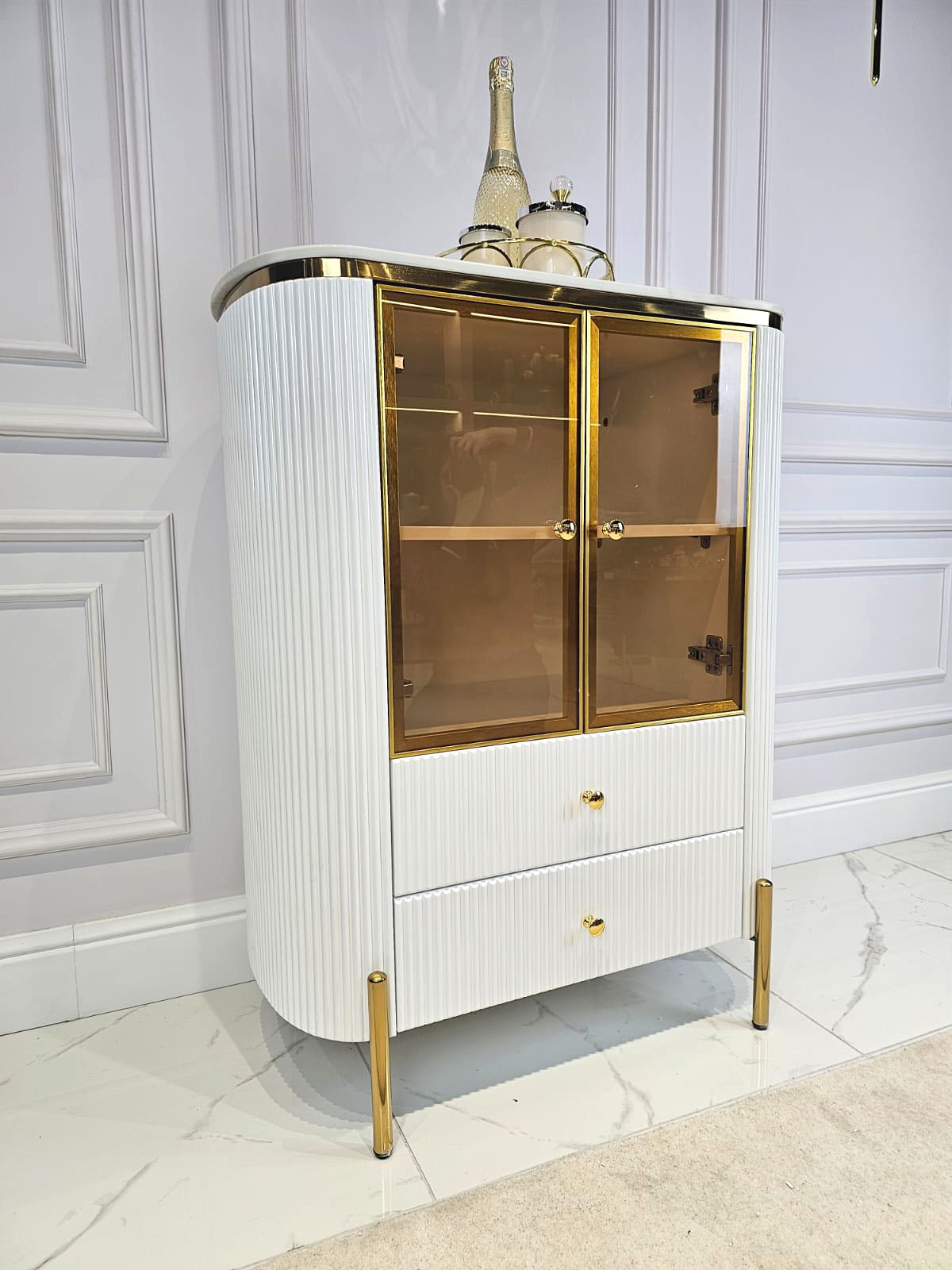 KOMODA Anne 2-drzwiowa, biały, ryflowany korpus, złote nóżki i metalowe detale, elegancka bursztynowa szyba KOMODA Anne 2-drzwiowa, biały, ryflowany korpus, złote nóżki i metalowe detale, elegancka bursztynowa szyba