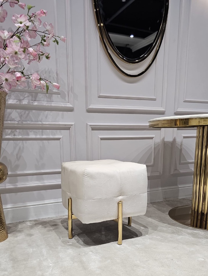 PUF na złotych, błyszczących nogach ze stali nierdzewnej, kwadratowe siedzisko obite białą, welurową tapicerką, eleganckie pikowanie, nowoczesny styl, piękny