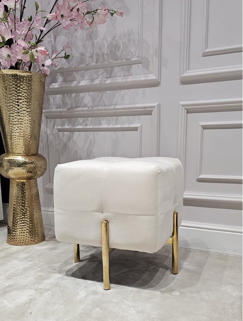 PUF na złotych, błyszczących nogach ze stali nierdzewnej, kwadratowe siedzisko obite białą, welurową tapicerką, eleganckie pikowanie, nowoczesny styl