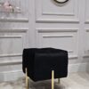 PUF na złotych, błyszczących nogach ze stali nierdzewnej, kwadratowe siedzisko obite czarną, welurową tapicerką, eleganckie pikowanie, nowoczesny styl, ekskluzywna