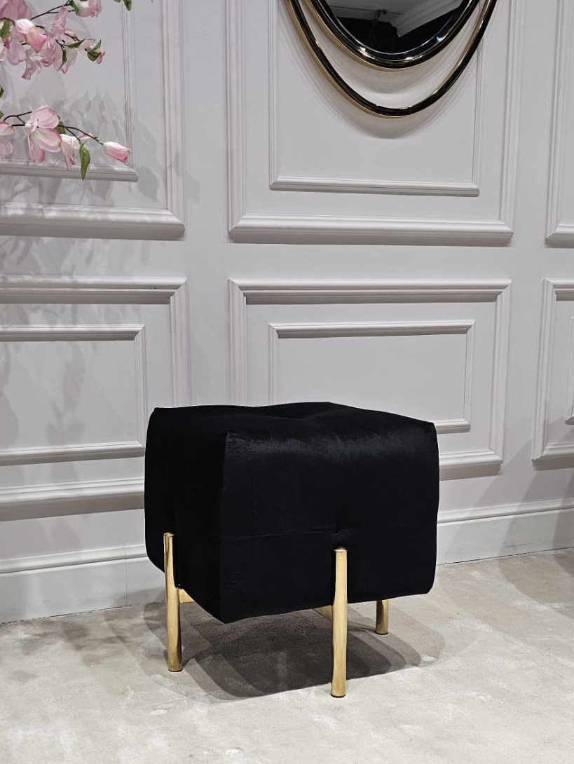 PUF na złotych, błyszczących nogach ze stali nierdzewnej, kwadratowe siedzisko obite czarną, welurową tapicerką, eleganckie pikowanie, nowoczesny styl, ekskluzywna
