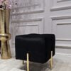 PUF na złotych, błyszczących nogach ze stali nierdzewnej, kwadratowe siedzisko obite czarną, welurową tapicerką, eleganckie pikowanie, nowoczesny styl
