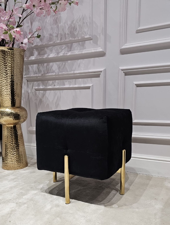 PUF na złotych, błyszczących nogach ze stali nierdzewnej, kwadratowe siedzisko obite czarną, welurową tapicerką, eleganckie pikowanie, nowoczesny styl